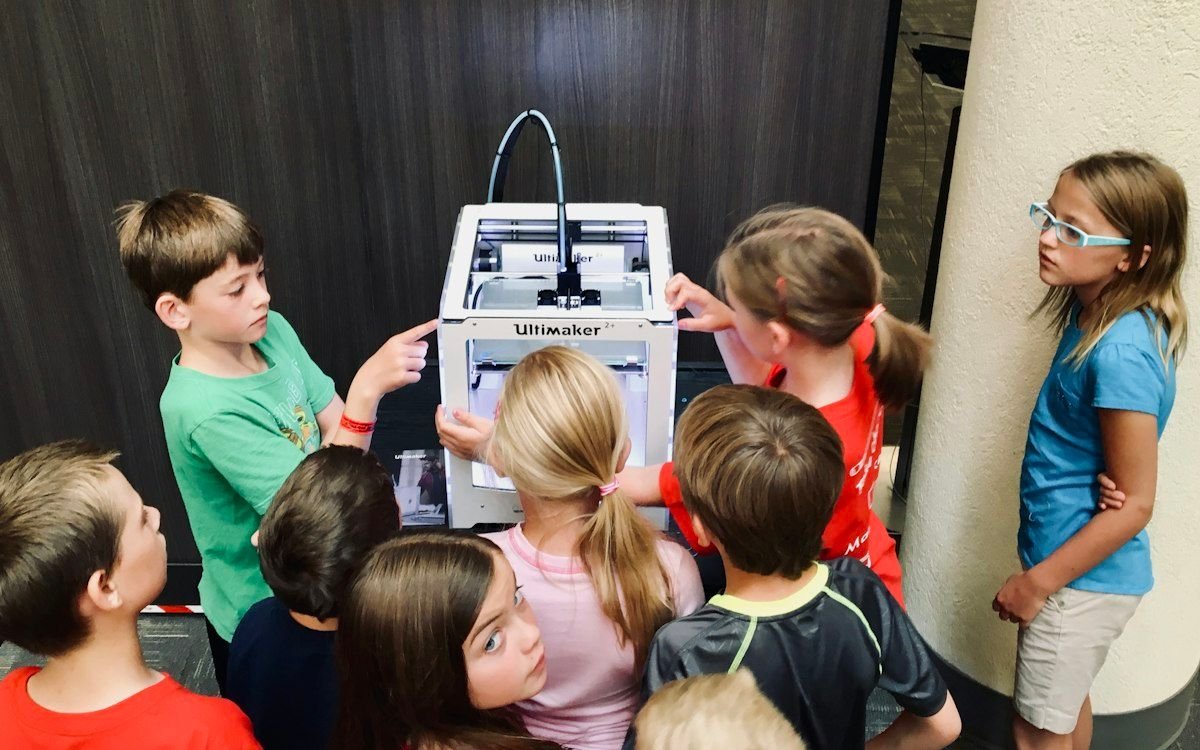 Niños observando una impresora 3D en funcionamiento